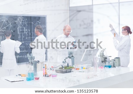 general-view of teacher and students working in chemistry lab seen trough a transparent board