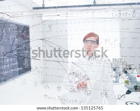 general-view of a student in a chemistry lab analyzing formulas and graphics on a transparent board