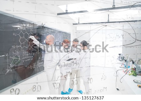 general-view seen trough a transparent board in a chemistry lab of people analyzing information
