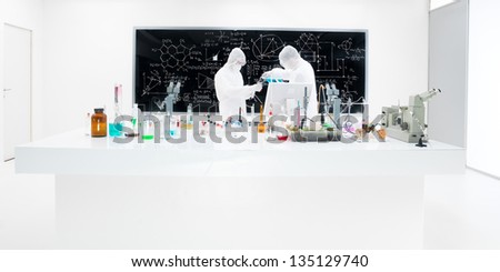 close-up of two scientists in a chemistry lab conducting an experiment around a lab table with colorful liquids, lab tools and magic gas with a blackboard on the background