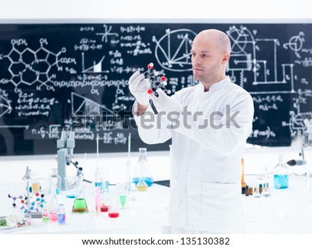 side-view of a scientist analyzing a  citric acid molecular model  in a chemistry lab around a lab table with colorful liquids and lab tools and a blackboard on the background