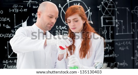 close-up of student observing a teacher conducting a lab experiment with colorful liquids  and lab tools and a blackboard on the background