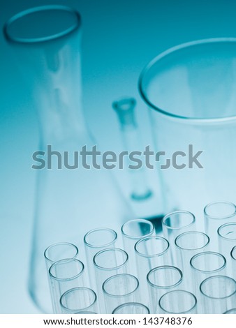 blue gradient background with empty laboratory glassware with test tubes, a beaker and an enlermeyer bottle in the background