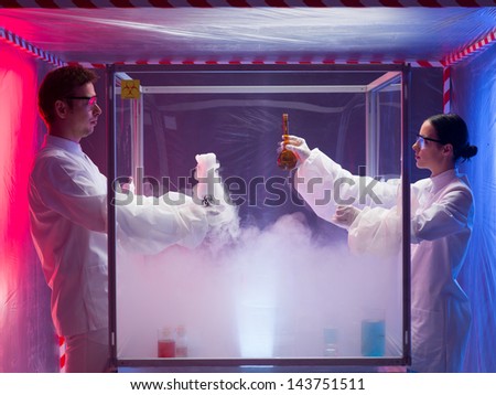 two scientists, a man and a woman, mixing chemicals in a sterile chamber labeled as bio hazardous filled with white steam, in a containment tent