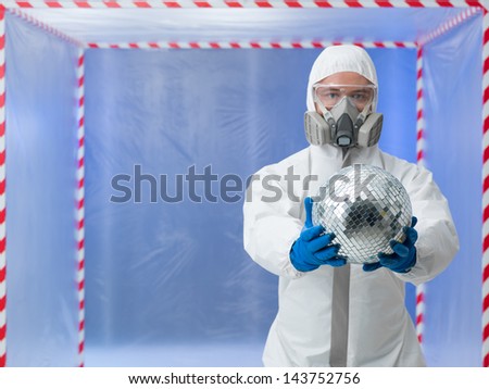 person dressed in a bio hazard protective suit showing a disco ball standing in front of a confinement tent