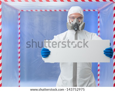 male scientist wearind protection equipment holding an empty ad banner, in a chamber surounded with red and white tape