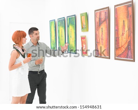 young caucasian couplemstanding in an art gallery contemplating and uderstanding artworks displayed on walls