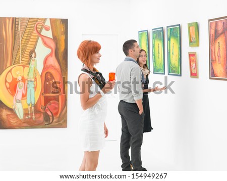young caucasian people in an art gallery looking at paintings and talking about them