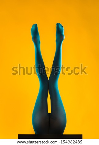 woman wearing blue stockings lying on her back with her legs up, holding her knees close to one and another making an x shape