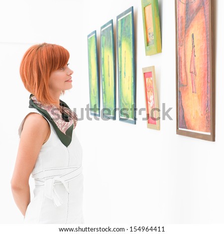 Side View Of Young Attractive Redhead Woman Standing In An Art Gallery Contemplating An Artwork