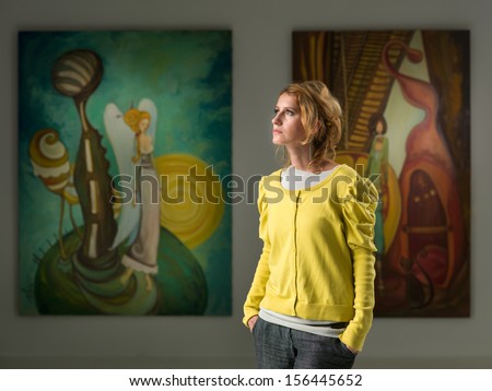 cropped view of caucasian woman standing and posing in an art gallery looking away