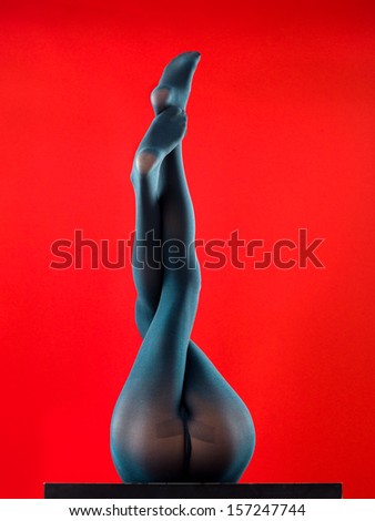 woman wearing tights lying on her back with her feet up on red background