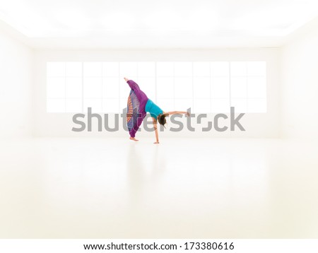 Beautiful woman with multicolored pants and blue shirt jumping in room