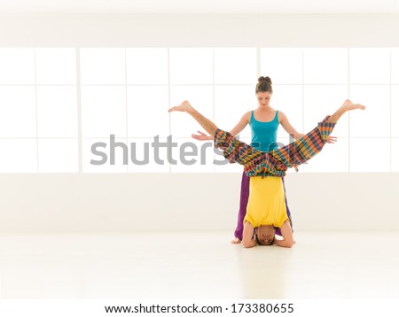 beautiful woman instructor with a handsome man dressed in vibrant colors are partners yoga in white gym