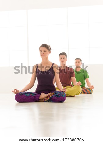 Three young people a woman and two men practice yoga class stand in line