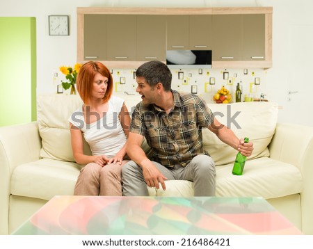 two young caucasian man and woman sitting on sofa having an argument