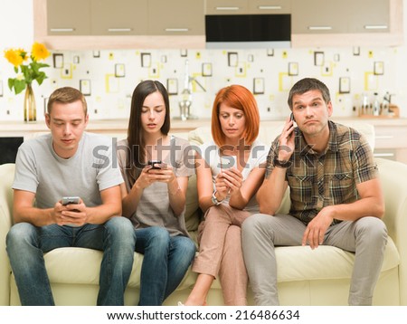 friends sitting on sofa and playing on their phones