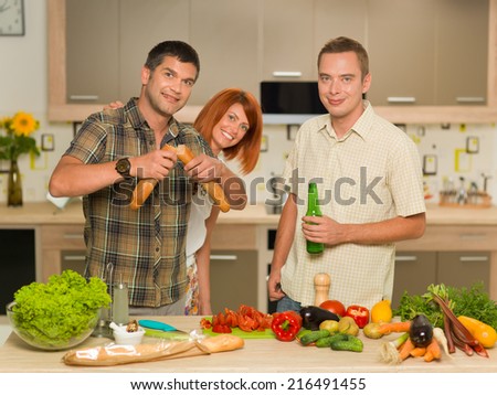 group of young people standing and having fun in kitchen, preparing food
