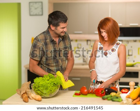 front view of young caucasian woman and man in kitchen preparing a salad