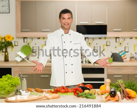 portrait of young caucasian male chef, standing with cut vegetables in front