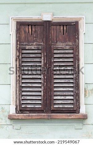 rustic old window closed with wooden exterior shutters