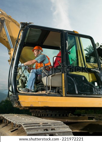 male worker operating excavator on construction site