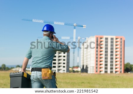 back view of caucasian enginner talking on phone at residential construction site