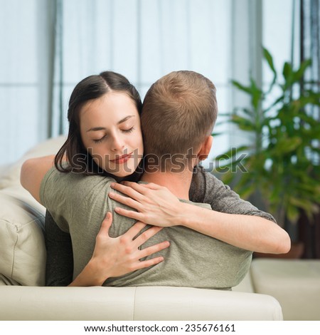 portrait of young caucasian couple relaxing on sofa at home, embracing each other