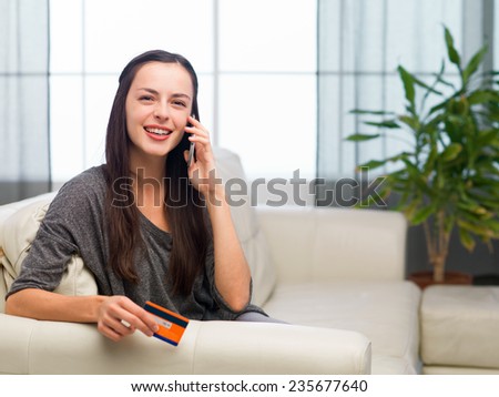 young happy caucasian woman holding credit card and shopping over the phone