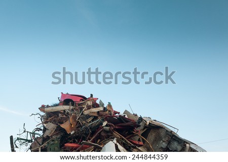 pile of scrap metal at recycling center, with clear blue sky