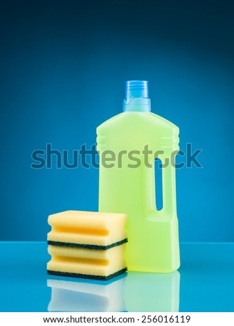 bottle of liquid detergent and sponges against blue background