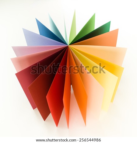 top view of colorful origami paper arranged in circle fan shape on white background