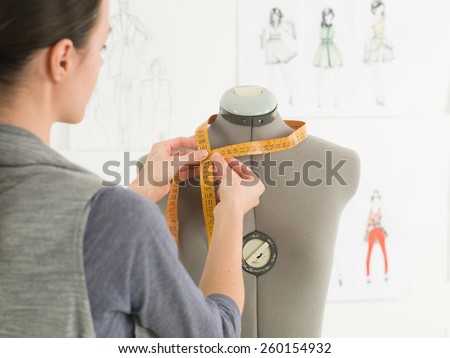 closeup of fashion designer measuring neck of dummy in a studio