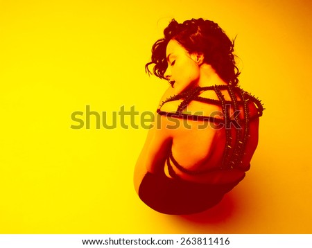 fashion shot of a beautiful caucasian model in squat pose, resting her head on knees with eyes closed. yellow toned image