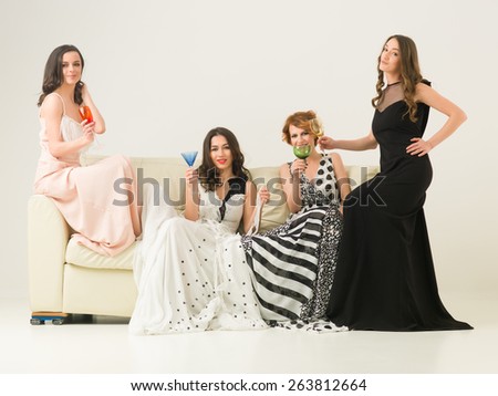 group of beautiful women sitting together on sofa celebrating with drinks