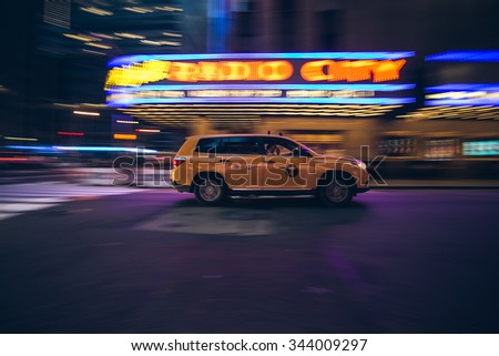 New York City - September 20: Manhattan night view of a yellow cab in motion in front of Radio City Concert Hall on 20 September 2015.
