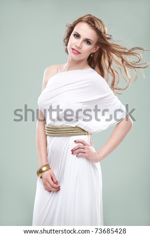 a studio portrait of a beautiful young woman, wearing a long, white, ancient greek inspired dress, smiling, with wind blowing in her hair.