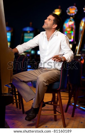 handsome man sitting by the slot machine, hoping to win