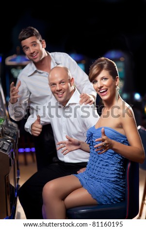excited woman winning at the slot machine, with happy friends cheering