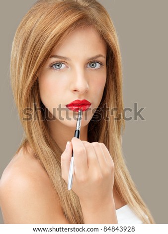 beautiful blonde woman applying red lipstick