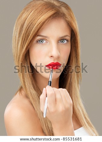 beautiful woman applying red lipstick brush