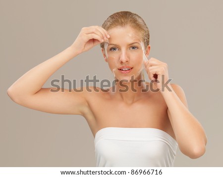 beauty portrait of beautiful blonde woman peeling off a facial mask, smiling