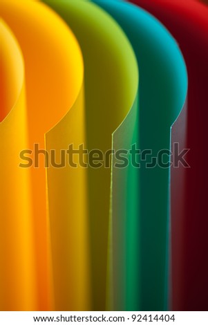 macro image of colorful curved sheets of paper shaped like a fan, on orange background