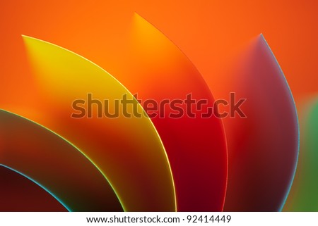macro image of colorful curved sheets of paper shaped like a fan, on orange background