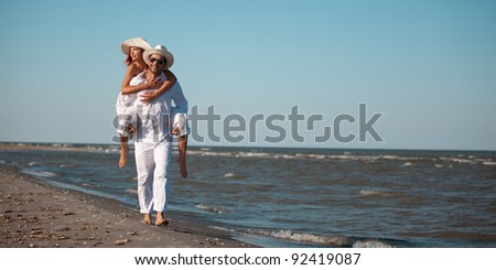 happy young couple dressed in white, on the beach, on a piggy back ride
