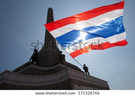 Bangkok, Thailand Ã¢Â?Â? January 13, 2014: Anti-government protester waves a big Thai flag on the Victory monument in Bangkok