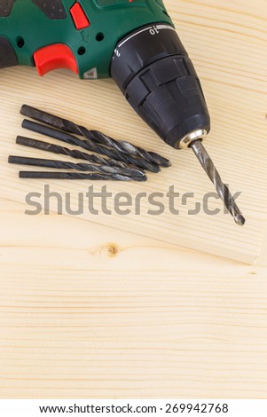 Electric drill and drill bits on a wooden board background