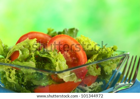 Fresh salad of lettuce and tomato (Selective Focus, Focus on the tomato slice in the middle of the photo)
