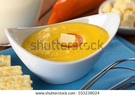 Peruvian Huancaina Sauce (spicy cheese sauce) in bowl with ingredients: cheese, crackers, aji (Peruvian yellow chili pepper) and milk (Selective Focus, Focus on the front of the cheese on the sauce)