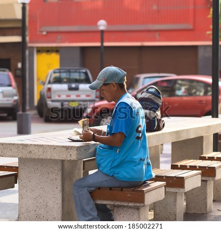LIMA, PERU - MARCH 5, 2012: Unidentified mobile money exchanger counting dollar bills at a table in Miraflores on March 5, 2012 in Lima, Peru. Money exchangers on the streets are common in Lima.